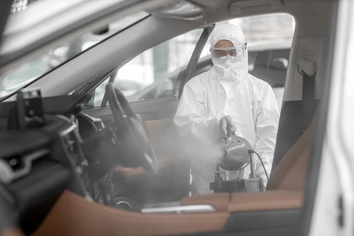 Main d'un jeune technicien masculin ayant une surface d'essuie-glace de la carrosserie jaune de la voiture tout en nettoyant le capot après réparation