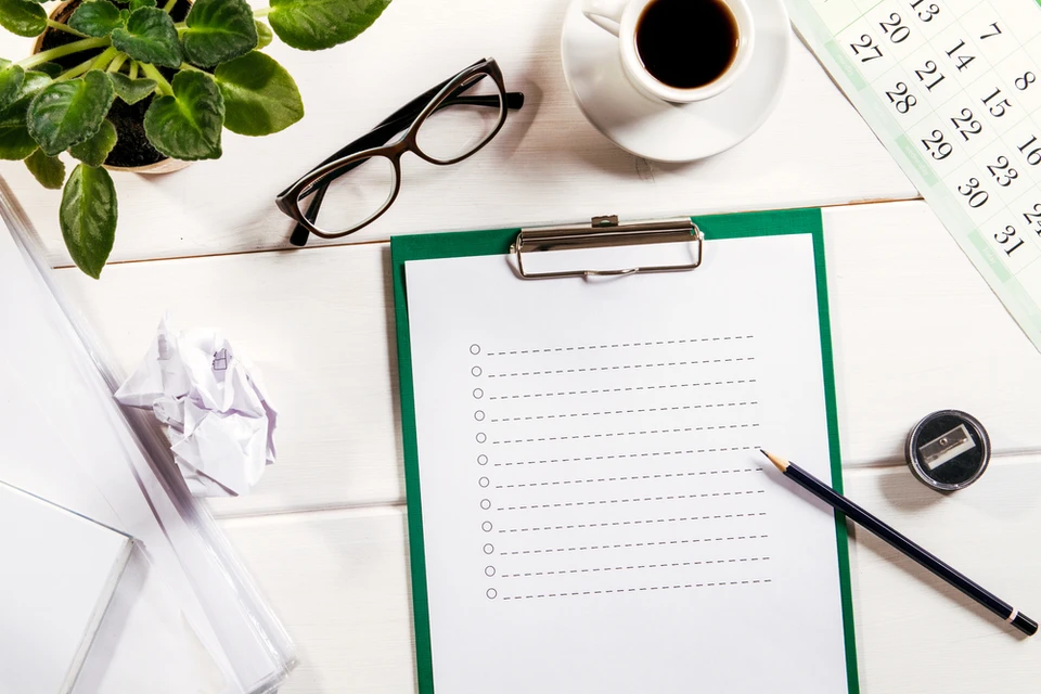 Bureau organisé avec clipboard à pince métallique contenant feuille lignée vierge, stylo noir posé dessus