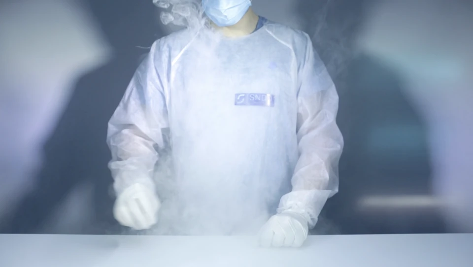 Professionnel en combinaison de protection intégrale grise avec masque respiratoire effectue une désinfection par pulvérisation dans un hall d'immeuble près d'un ascenseur